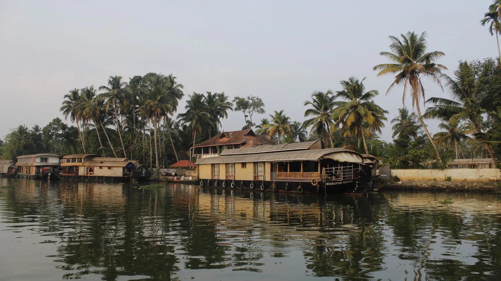 A traditional Kerala houseboat gliding through palm-lined backwaters at golden hour